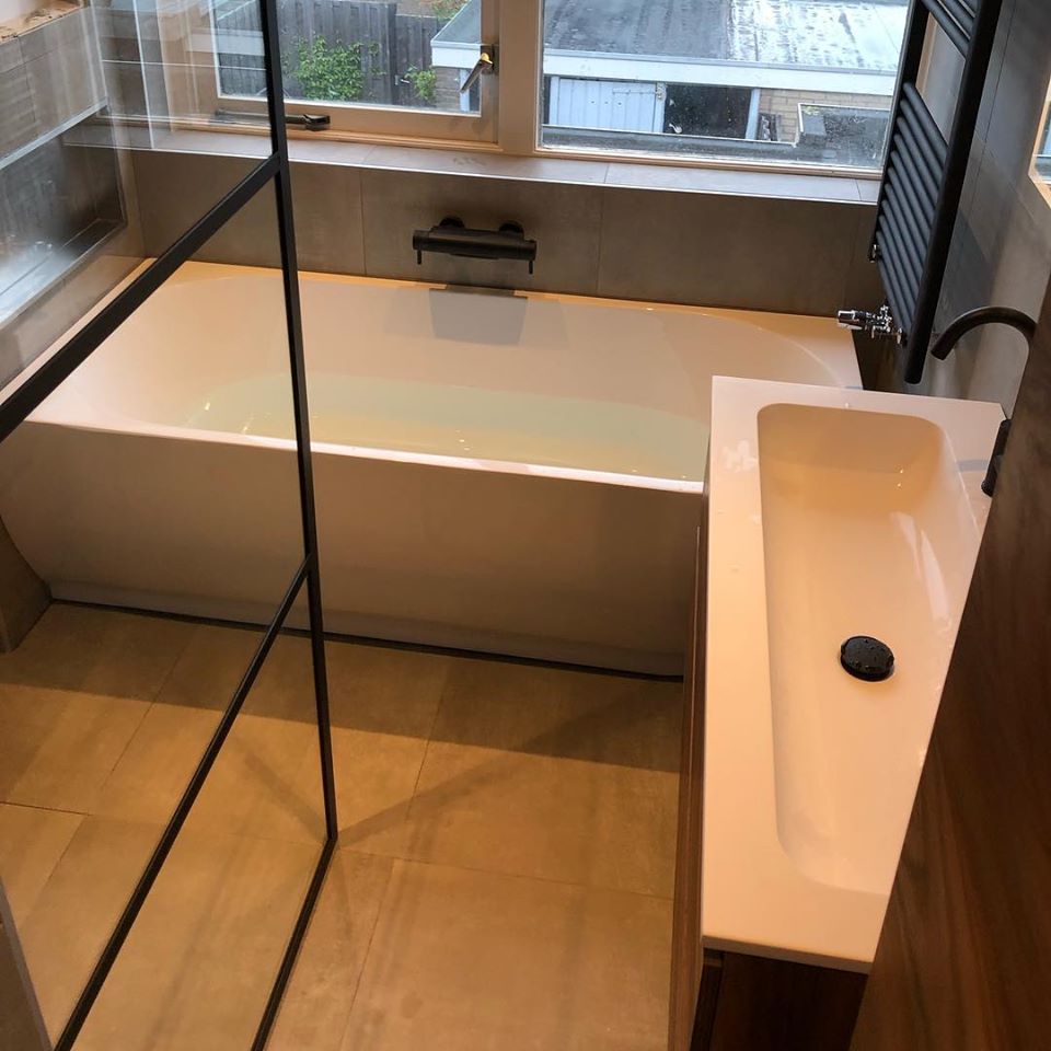Badkamer met ligbad en bruin badkamermeubel
